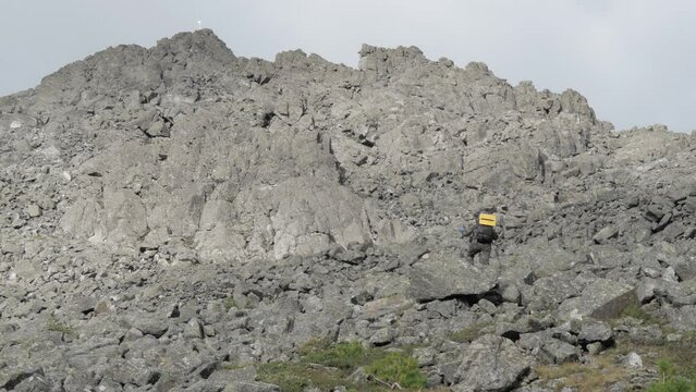 A woman climbs a mountain with a backpack. The tourist climbs to the top of the mountain. An aged woman travels. Ural mountains. Mount Silverstone.
