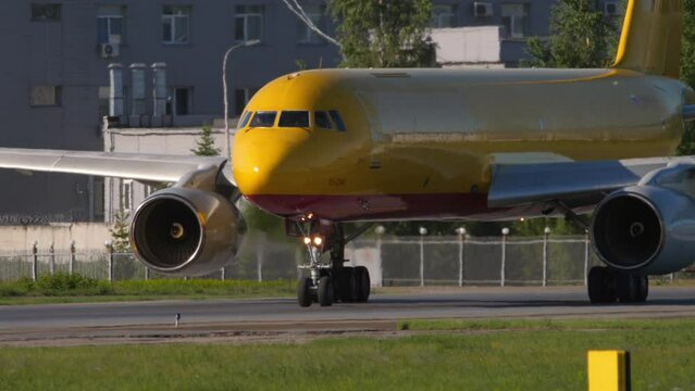 NOVOSIBIRSK, RUSSIAN FEDERATION - JUNY 12, 2022: Middle shot of cargo plane Tupolev of Aviastar-TU taxiing. Transport airline. Aircraft with yellow livery on the taxiway