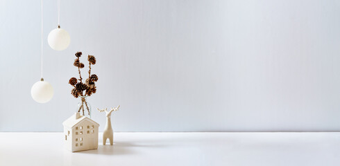 Christmas, New Year home decor. Empty white wall mock up with christmas little house and deer on a white table. Mock up for displaying works