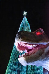 A tyrannosaurus rex with glowing red eyes guards the Christmas light tree, the focal point of the Illumi light festival in Mississauga, Ontario. © John