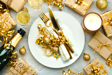 Christmas dinner concept. Top view of golden cutlery on a plate with christmas ornament and champagne bottle. Christmas concept background