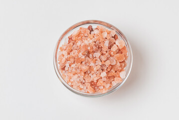 Top view of of a glass small bowl  with Himalayan coarse salt isolated  on white background