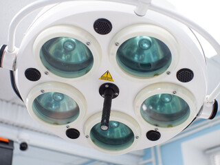 An electric operating lamp hangs from the ceiling in surgery. A surgical lantern is installed above the table in the operating room. Close-up. Surgical equipment concept.