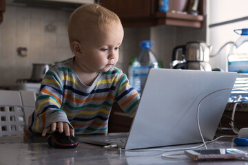 Fototapeta na wymiar Little baby curiously looking at laptop surfing in internet