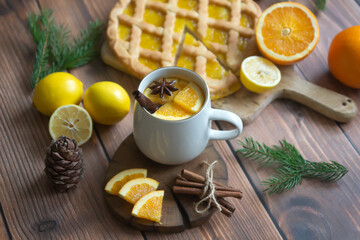 Aromatic tea with orange and spices on a wooden table. Pie, lemons, oranges winter mood.