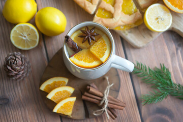 Aromatic tea with orange and spices on a wooden table. Pie, lemons, oranges winter mood.