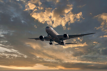 horizontal image with copy space of a plane landing full of passengers against the blue sky at a beautiful sunrise