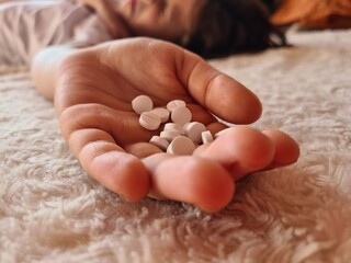 Girl child took large dose of pills and lies on bed.