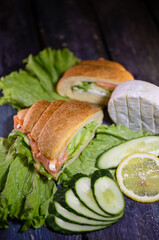 fresh croissant with salmon and lettuce leaf on a wooden background