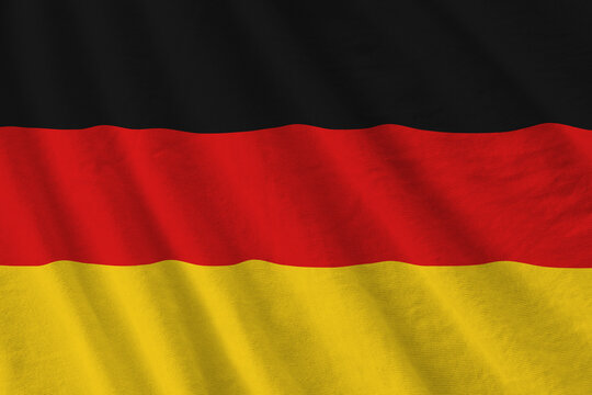 Germany flag with big folds waving close up under the studio light indoors. The official symbols and colors in banner