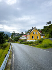 Fototapeta na wymiar road in the country of norway with a typical norwegian yellow house