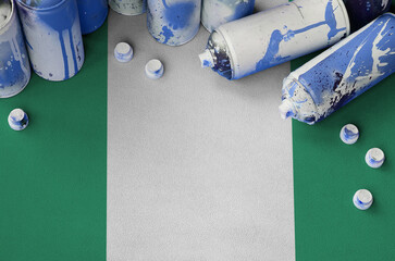 Nigeria flag and few used aerosol spray cans for graffiti painting. Street art culture concept