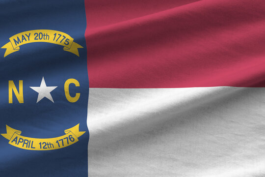 North Carolina US state flag with big folds waving close up under the studio light indoors. The official symbols and colors in banner