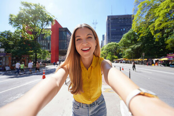 Tourism in Sao Paulo. Beautiful smiling girl takes self portrait on Paulista Avenue, Sao Paulo,...