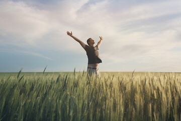 Fototapeta na wymiar Happy man raise hands on wheat field and sky soft landscape. Light delicate pastel color tone. Nature horizontal background with copy space.