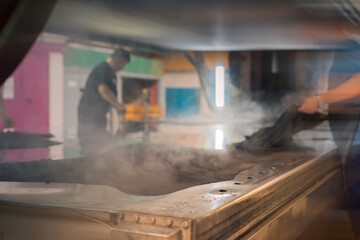 Steam from the skin when leveling and processing leather products at the factory in the workshop...