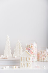 Merry Christmas decoration concept with candles and festive decor, colorful marshmallows, christmas trees on light white background. Cozy home. Space for text.