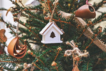 Vintage wooden toy house on Christmas tree. Natural Xmas ornaments for Christmas tree, zero waste, soft focus