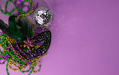 background for Mardi Gras with purple, green and yellow beads, carnival mask and disco ball