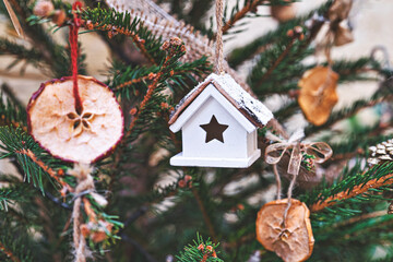 Vintage toy house and dried apple on Christmas tree. Natural DIY ornaments for Christmas tree, zero waste Christmas, soft focus