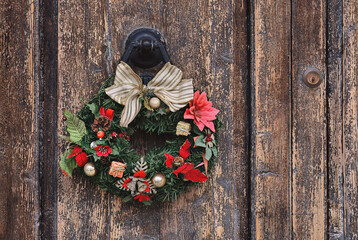 Christmas crown wreath upon an old wooden door. Traditional home decor during Christmas, copy space