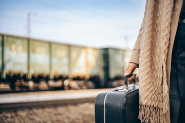 woman on railway station  with a retro suitcase