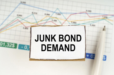 Against the background of business graphics and pens, a sign with the inscription - JUNK BOND DEMAND