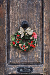 Christmas crown wreath upon an old wooden door. Traditional home decor during Christmas, vertical