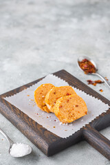 Butter with paprika and salt, cut into circles, on a brown wooden board on a gray concrete background. Types of butter for serving dishes. French cuisine