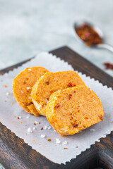 Butter with paprika and salt, cut into circles, on a brown wooden board on a gray concrete background. Types of butter for serving dishes.