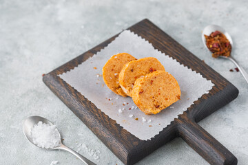 Butter with paprika and salt, cut into circles, on a brown wooden board on a gray concrete background. Types of butter for serving dishes.