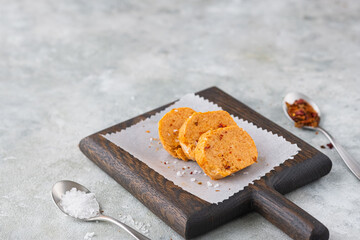 Butter with paprika and salt, cut into circles, on a brown wooden board on a gray concrete background. Types of butter for serving dishes.