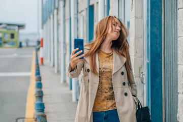 Obraz premium middle-aged woman walking on the street in autumn with mobile phone