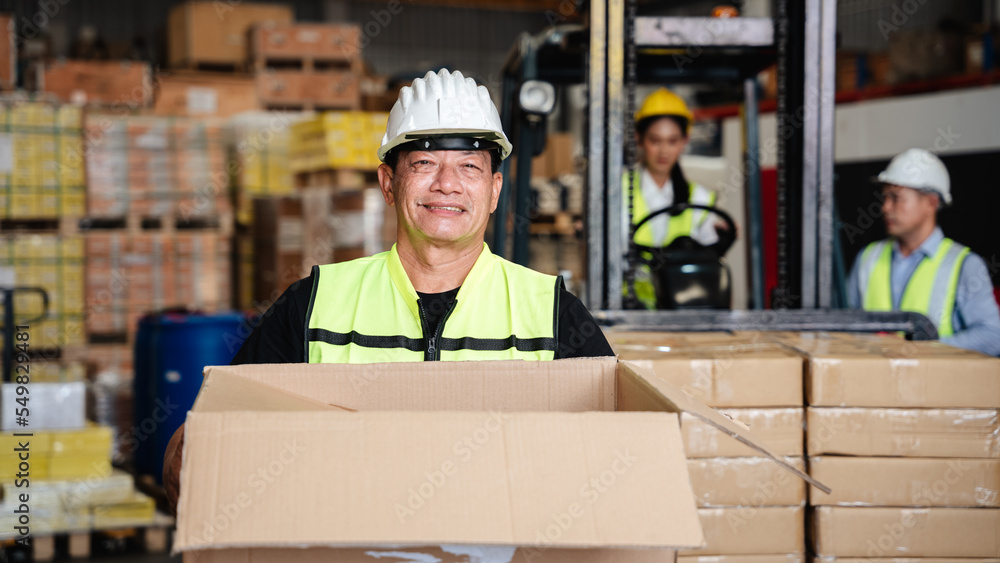 Wall mural Warehouse worker holding box in a warehouse or storehouse.