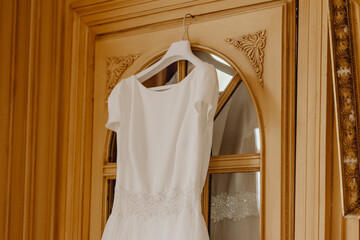 Fototapeta na wymiar Robe de mariée suspendue sur la porte de la chambre