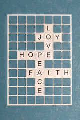 Mots croisés avec les mots Amour, Joie, Espoir, Paix, Foi. Concept de foi sur une grille de mots sur fond uni bleu.