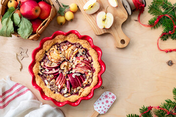 Homemade cake with cranberry jam and fresh red apples on a wooden background. Apple pie for New Year and Christmas.