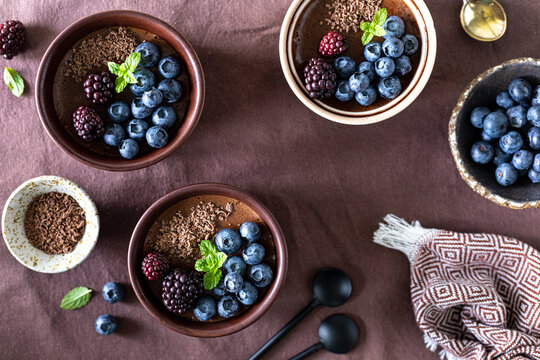 Delicious chocolate mousse or panna cotta with blueberries and blueberries on a dark fabric background.