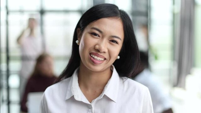 Happy young Asian saleswoman looking at camera welcoming client.