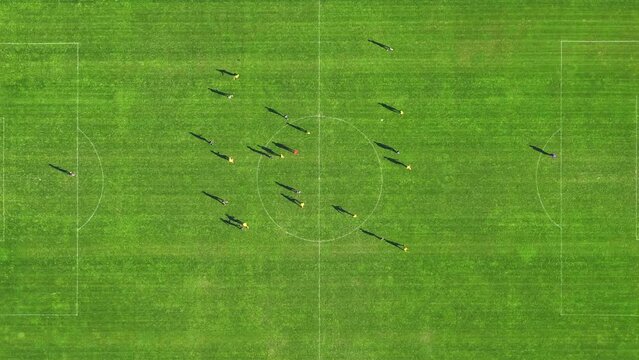 The camera flies over the green football field where professionals run and compete with each other. A football match filmed from a drone with a parallax effect