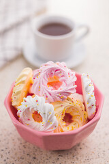 Different colors meringues with sprinkles in pink bowl.