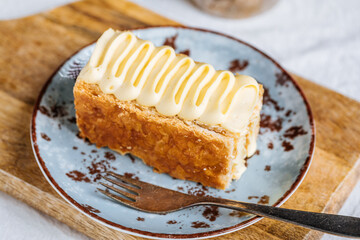 French dessert called Mille Feuille or Napoleon cake on rustic wooden board. Layered tasty cake with vanilla cream and puff pastry.
