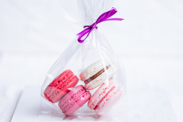 Close up of Macaroons in different colours on bright white background with subtle reflection on marble tray. Popular merengue dessert with filling inside. 