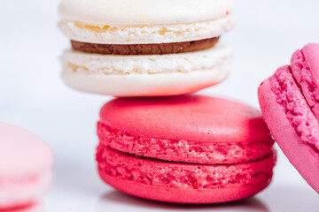 Close up of Macaroons in different colours on bright white background with subtle reflection on marble tray. Popular merengue dessert with filling inside. 