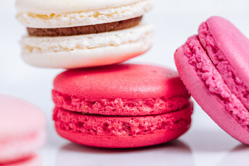 Close up of Macaroons in different colours on bright white background with subtle reflection on marble tray. Popular merengue dessert with filling inside. 