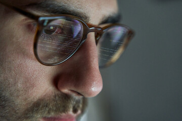Programmer working on code. Lines of code reflected in glasses. Developing software and website