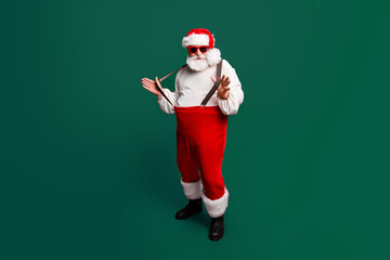 Full length body size of cheerful positive optimistic glad Santa pulling pants suspenders ready to feast festive party congrats congratulations best wishes sale discount isolated over red background