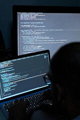 Vertical shot of male writing coding on three screens. Software programmer and web developer
