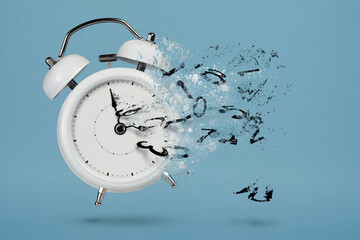 Time is running out. White alarm clock with flying numbers as a symbol of lost time. The concept of...
