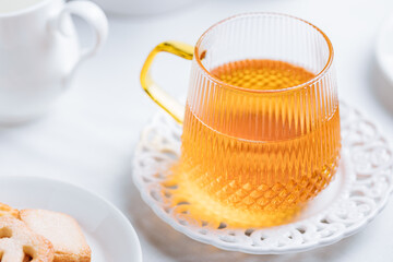 Cookies and tea in glass mug served in bright Christmas atmosphere. Bright and light scene setup.